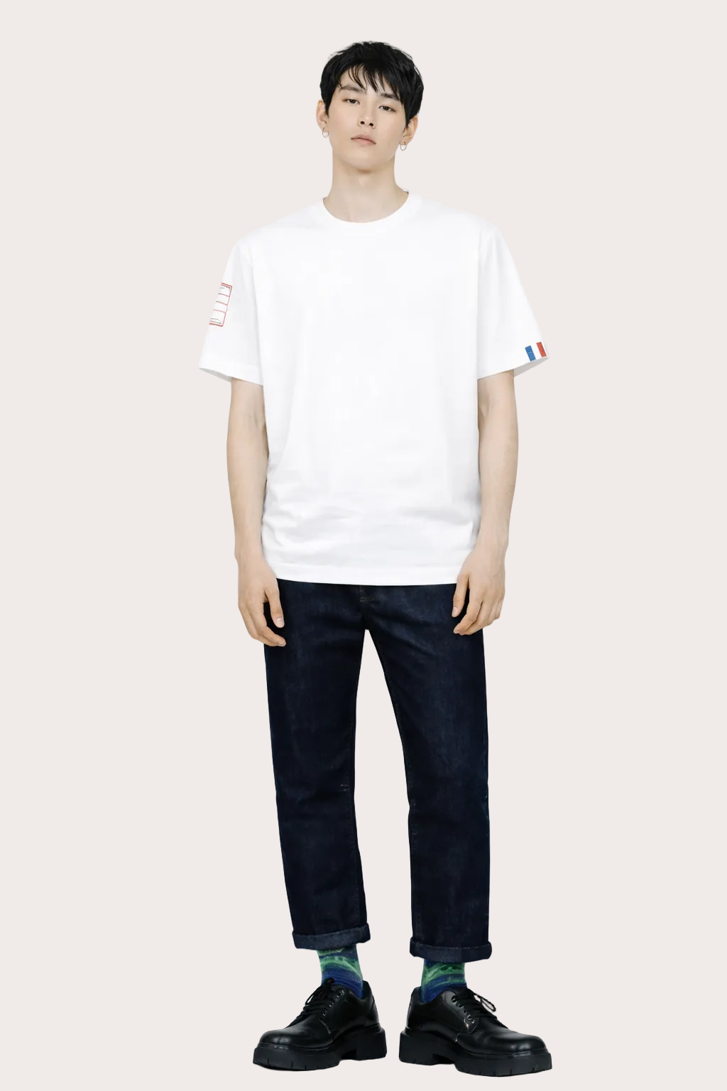 Vue de face du T-shirt  Vague blanc unisexe en coton biologique certifié GOTS, coupe droite avec détail tricolore signature sur la manche gauche.